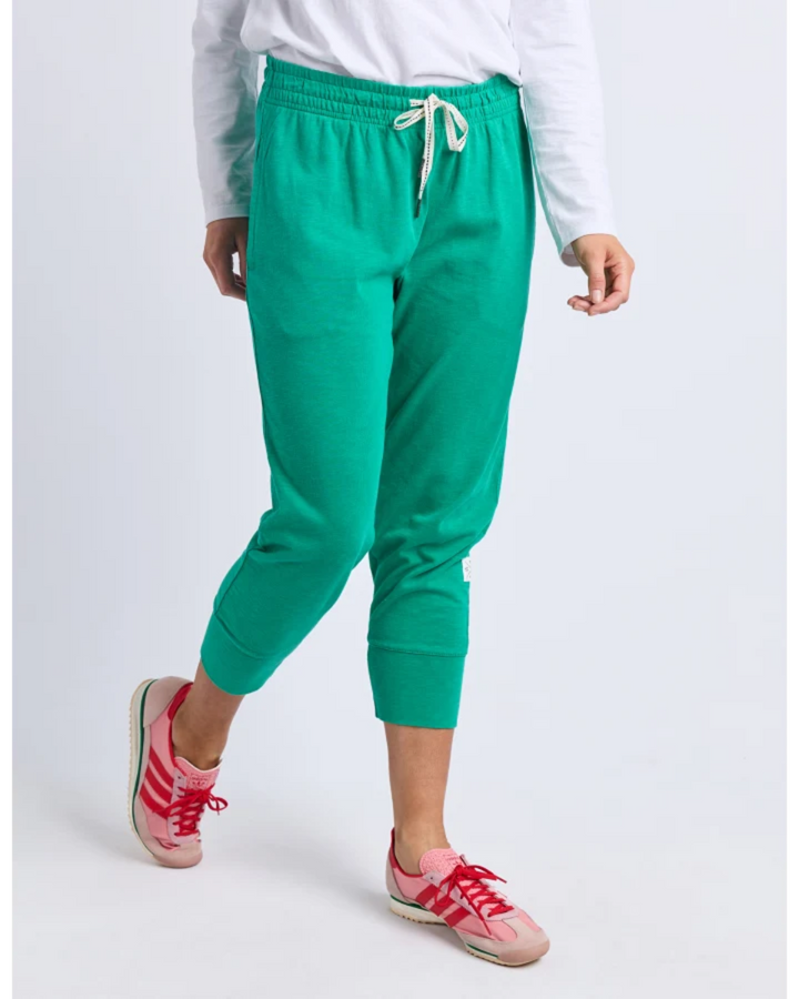 Person wearing green jogger pants and pink sneakers on a white background