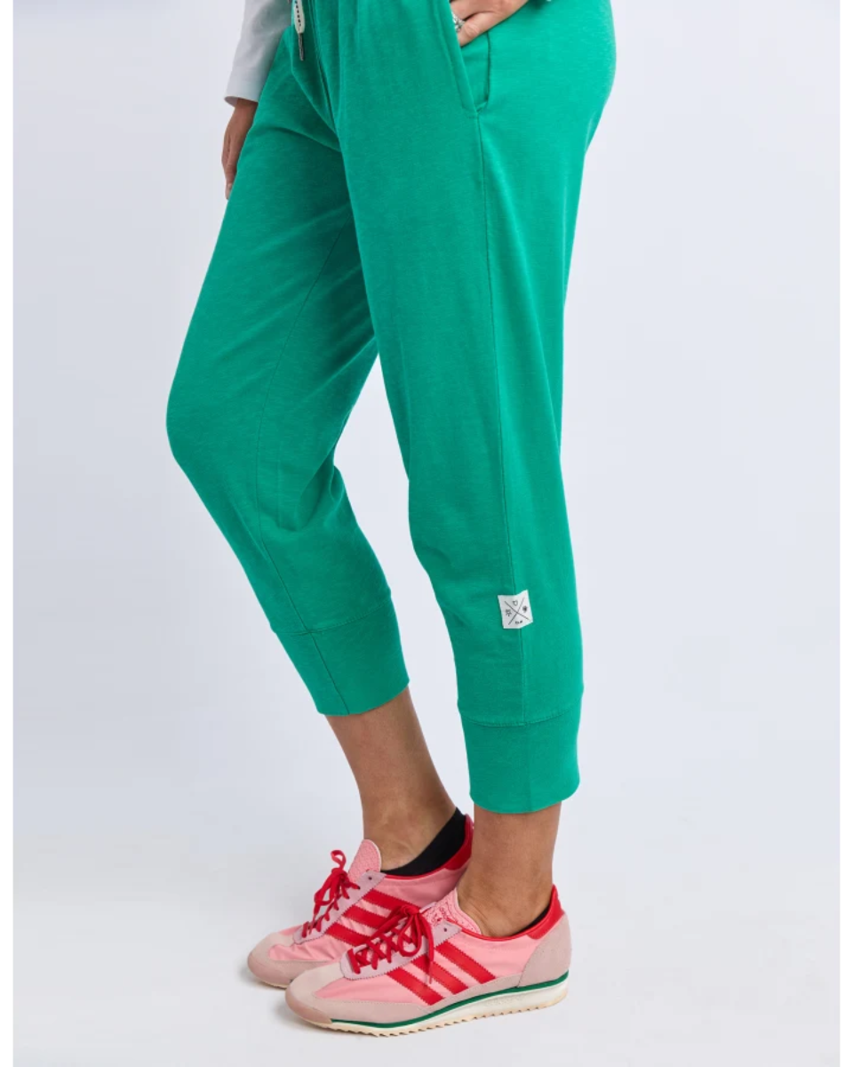 Close-up of teal jogger pants with cuffed hem and sneakers.
