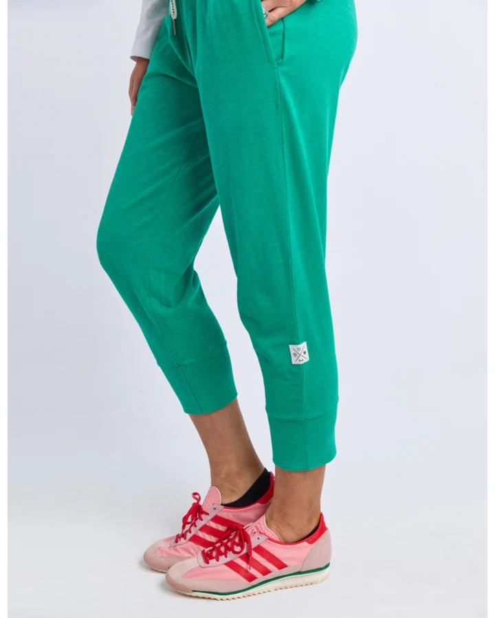 Close-up of teal jogger pants with cuffed hem and sneakers.