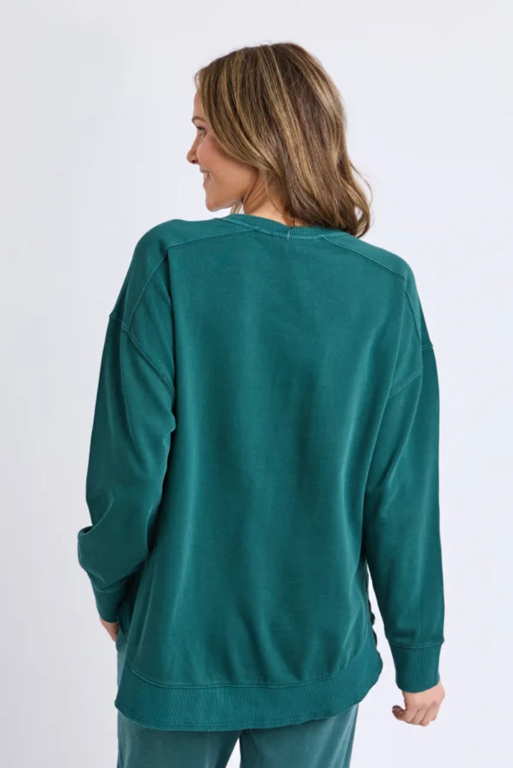 Person wearing a teal long-sleeve top on a white background