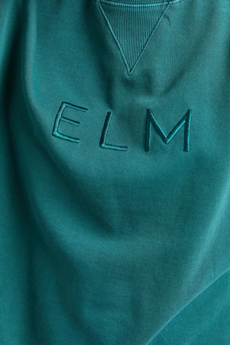 Teal sweatshirt with 'ELM' branding on a plain background