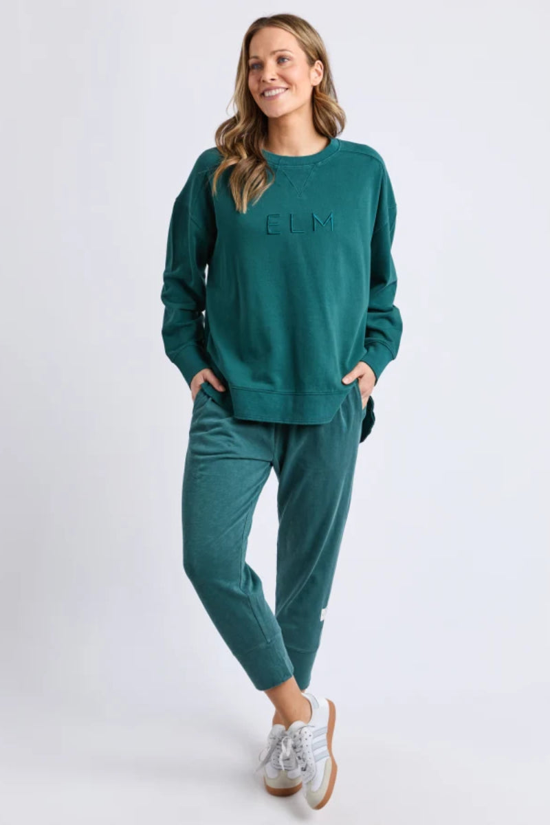 Woman wearing a teal tracksuit with 'GIM' branding on a white background