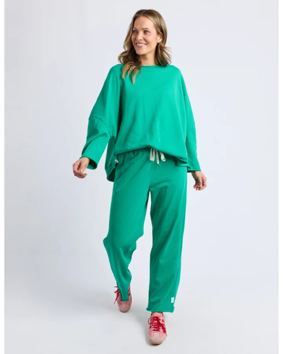 Woman wearing a green outfit with red shoes on a white background