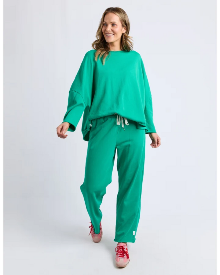 Woman wearing a green outfit with red shoes on a white background