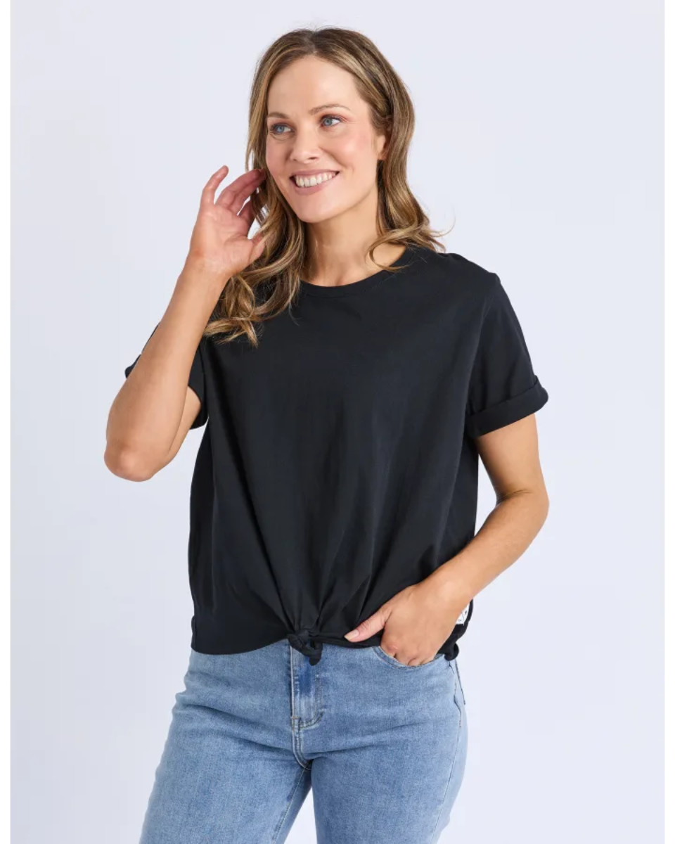 Woman wearing a black t-shirt and blue jeans on a light gray background
