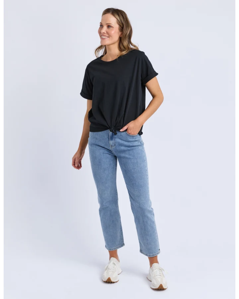 Woman wearing a black t-shirt and light blue jeans on a white background