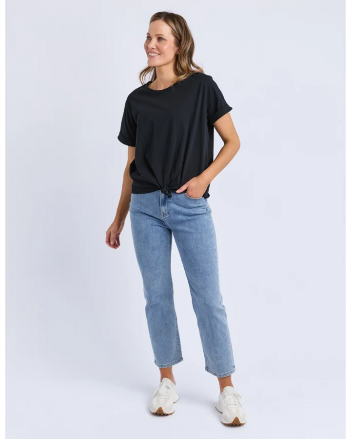 Woman wearing a black t-shirt and light blue jeans on a white background