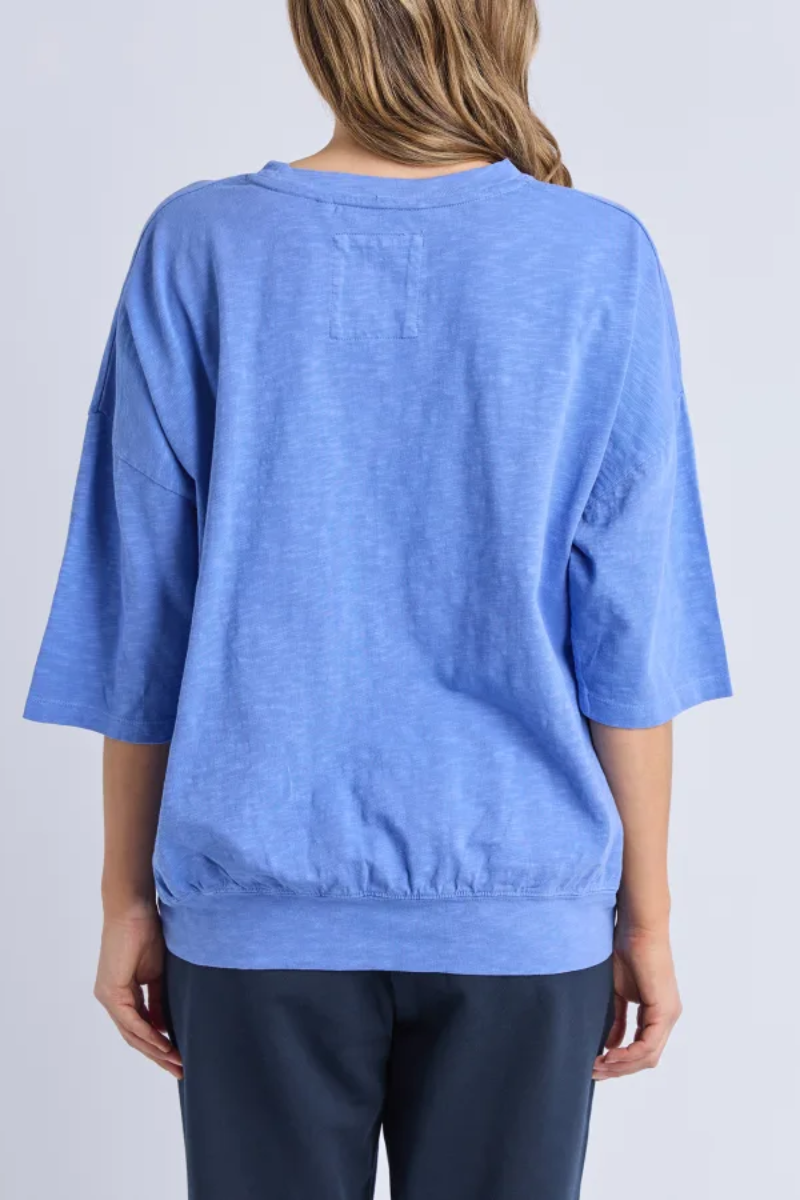Person wearing a blue oversized shirt on a plain background