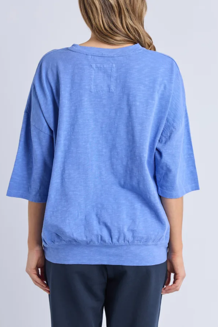 Person wearing a blue oversized shirt on a plain background
