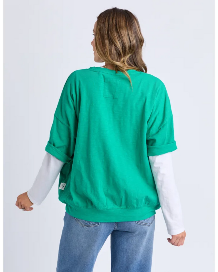 Back view of green loose-fit top with rolled sleeves.