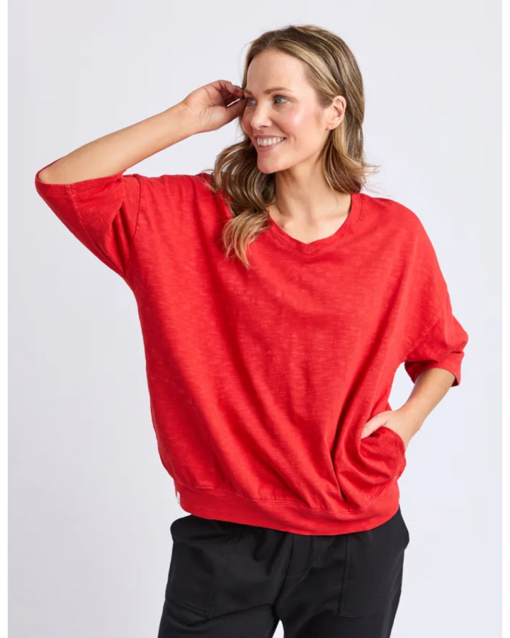 Woman wearing a red sweater and black pants on a white background