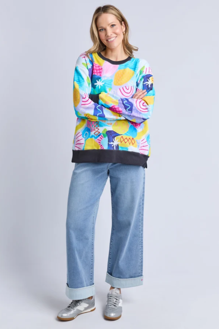 Person wearing a colorful sweater and jeans on a light gray background