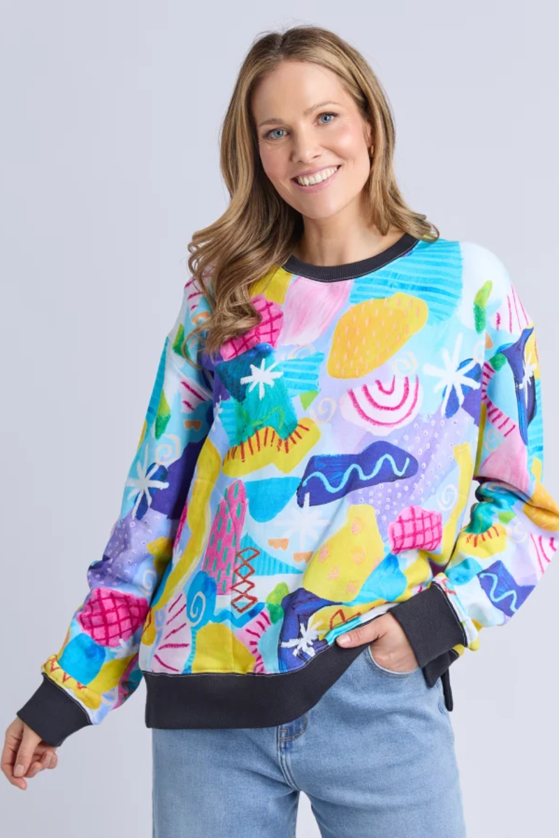 Woman wearing a colorful patterned sweater against a plain background