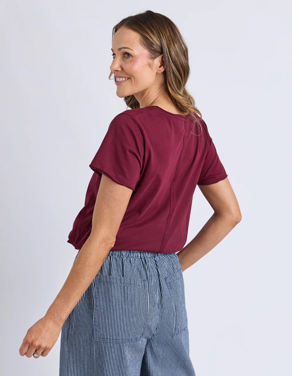 Woman wearing a maroon top and blue striped pants against a white background