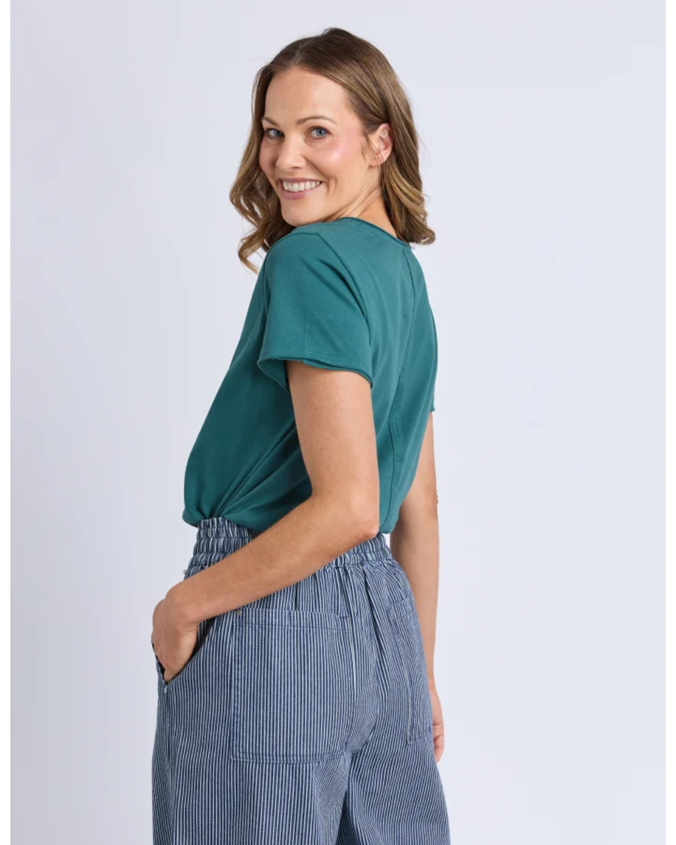 Woman wearing a teal top and blue striped pants on a light gray background