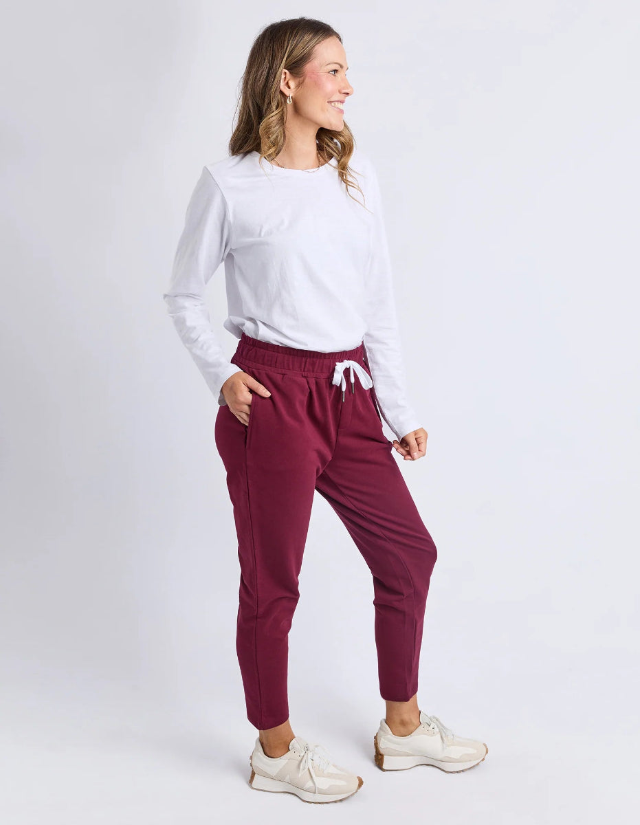 Woman wearing a white shirt and maroon pants on a white background