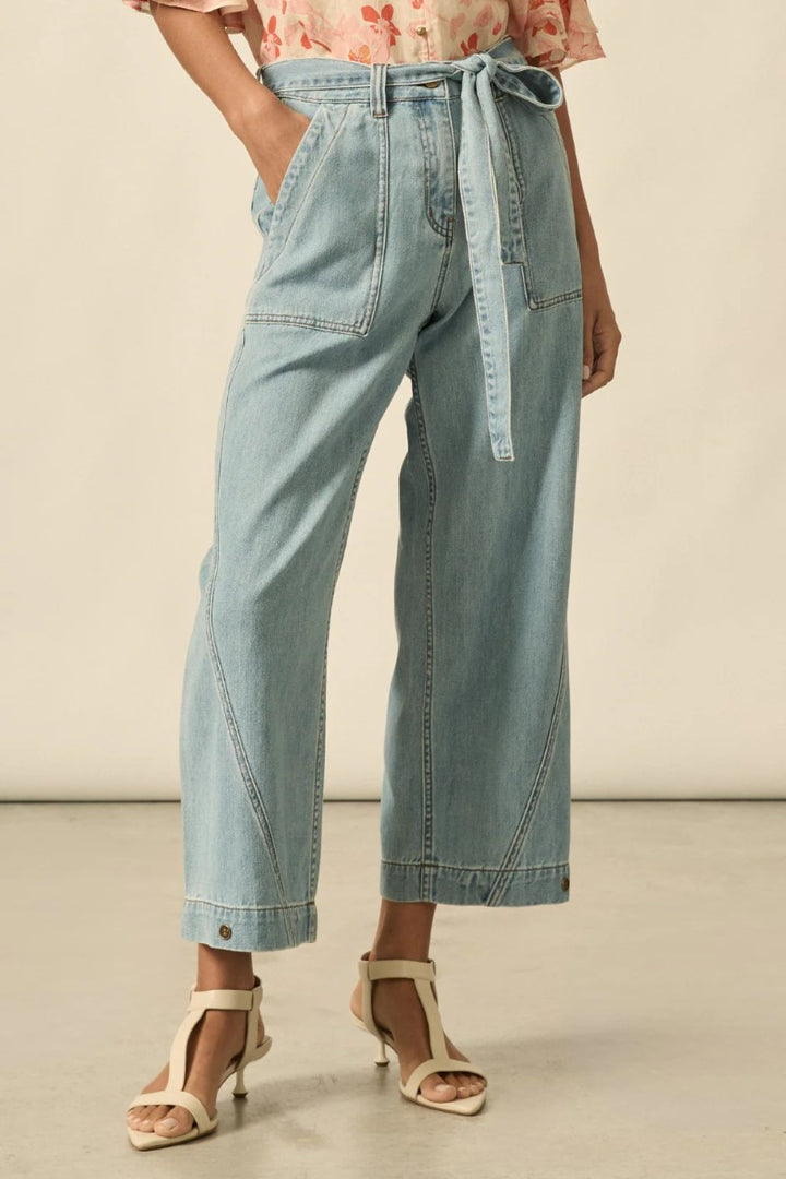 Light blue denim pants with a tie waist worn by a person on a neutral background
