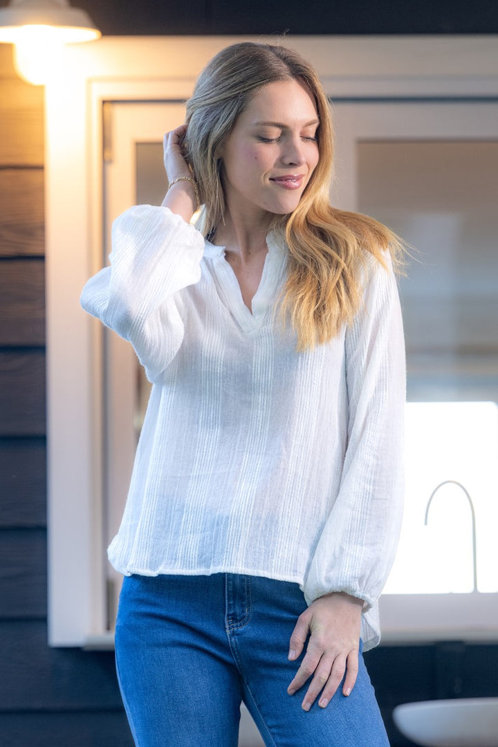 Woman wearing a white blouse and blue jeans indoors