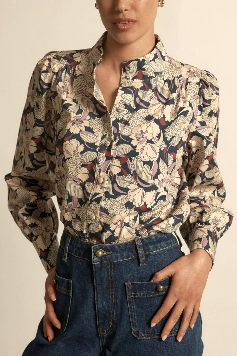 Woman wearing a long sleeve berry garden button down in beige background.