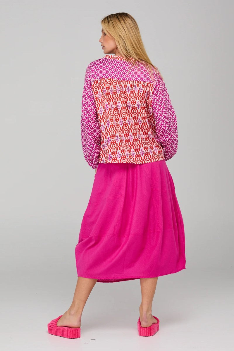 Woman wearing a pink patterned jacket and pink skirt on a white background