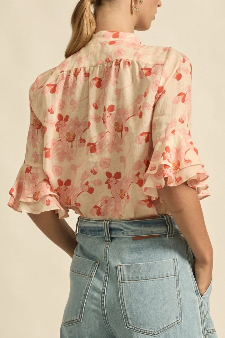 Woman wearing a floral blouse and jeans on a beige background