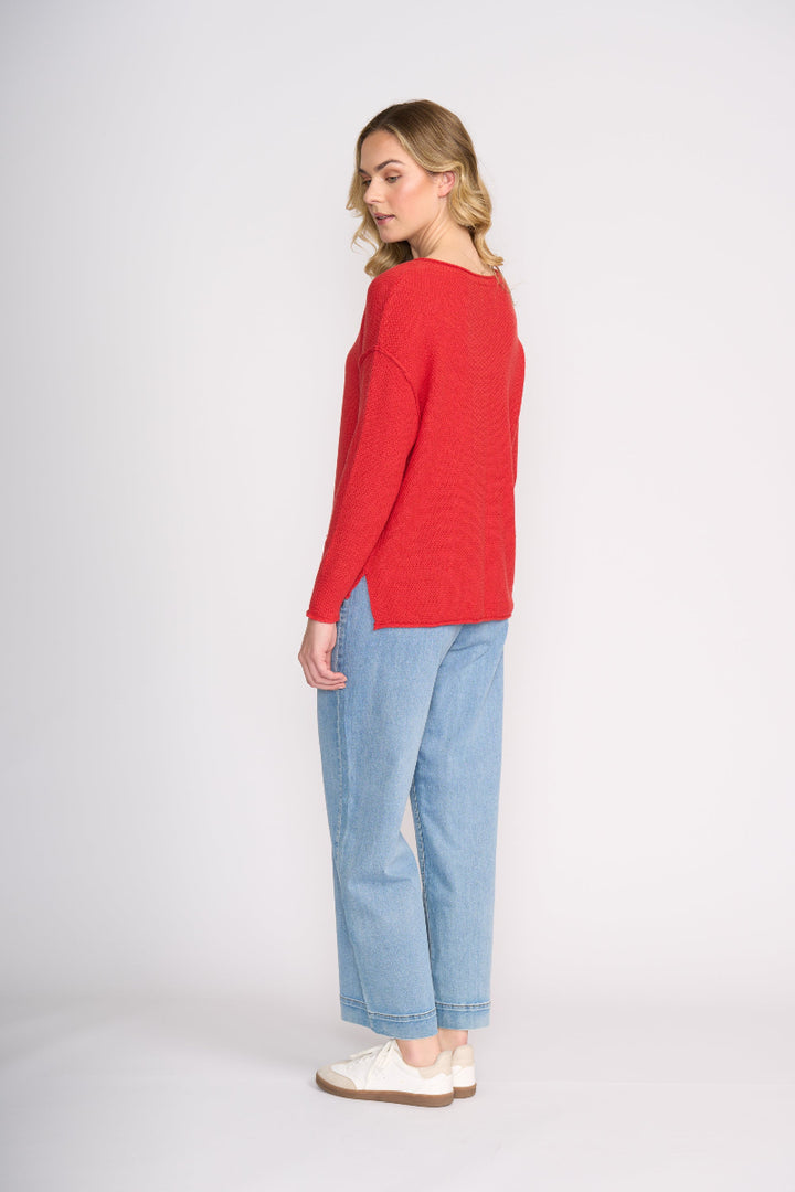 Woman wearing a red sweater and blue jeans on a white background