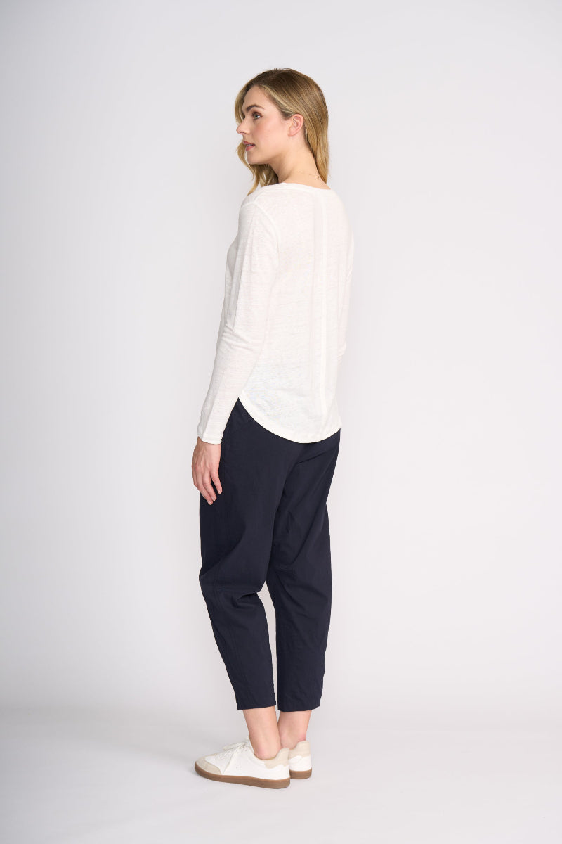Woman wearing a white top and navy pants on a white background