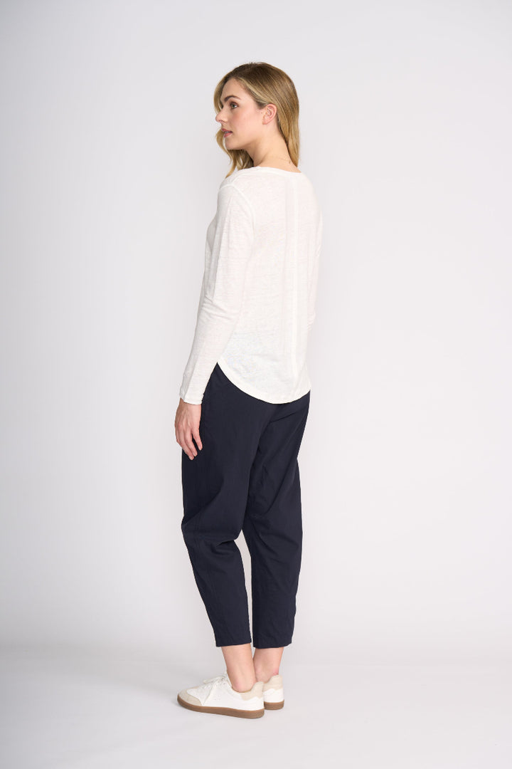 Woman wearing a white top and navy pants on a white background
