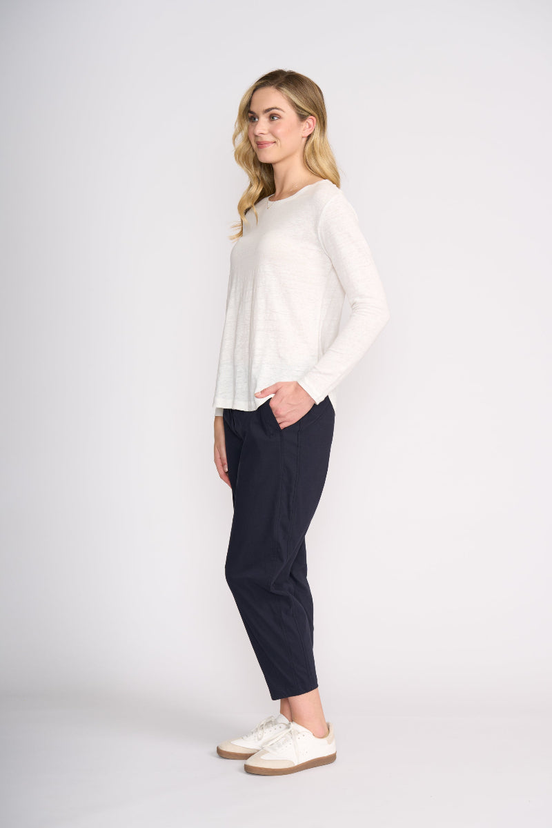 Woman wearing a white top and navy pants on a white background