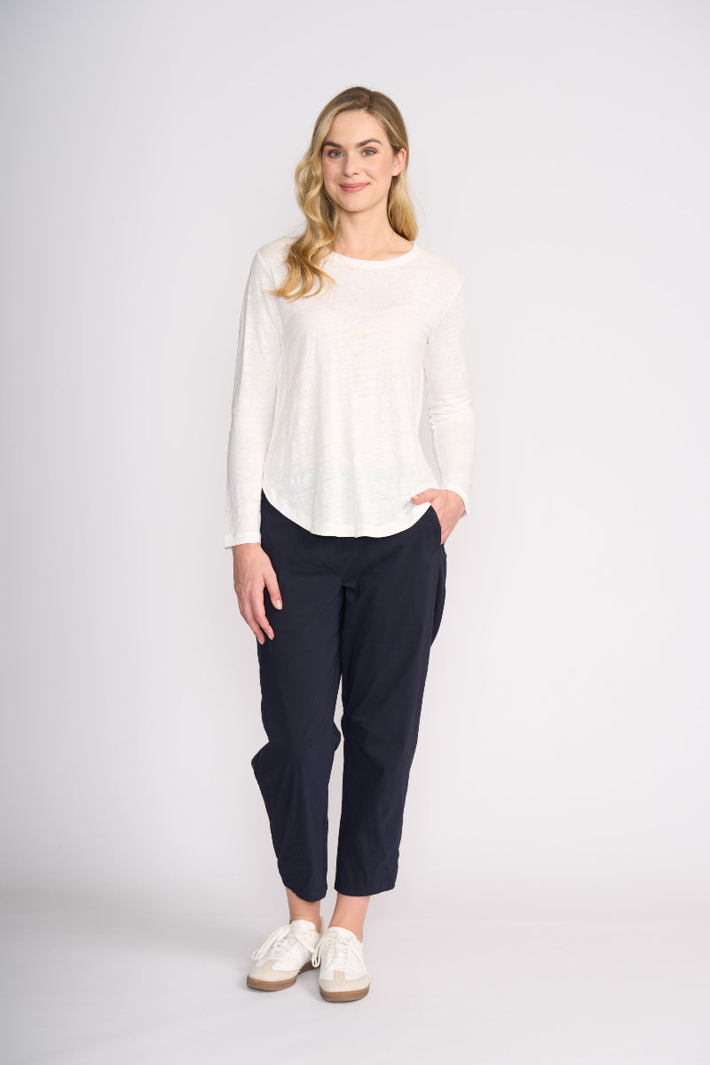 Woman wearing a white top and navy pants on a white background