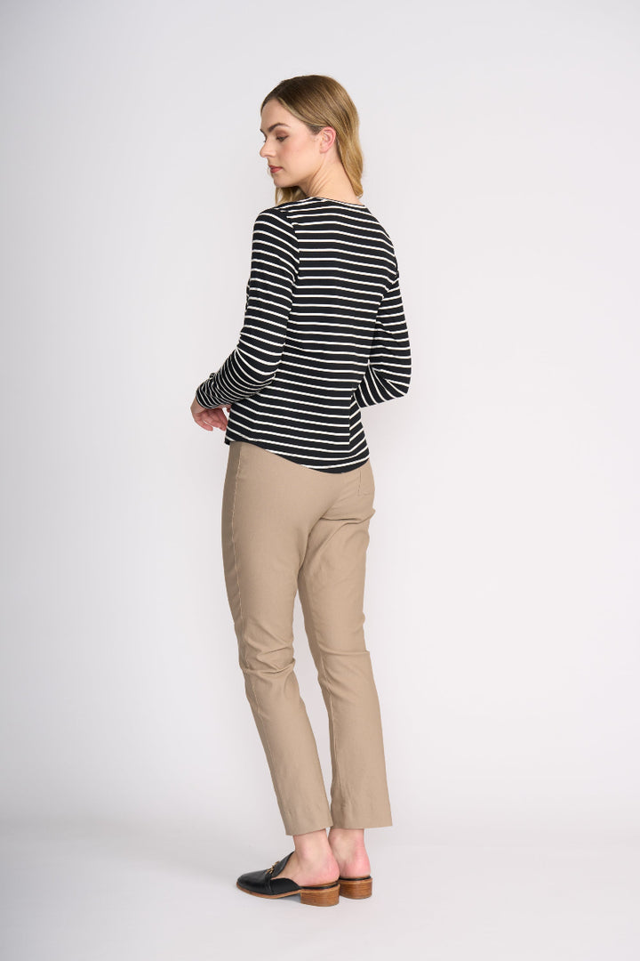 Woman wearing a black and white striped sweater and beige pants on a white background
