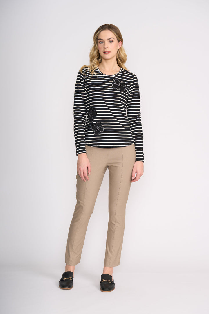 Woman wearing a black and white striped sweater with floral embellishments on a white background