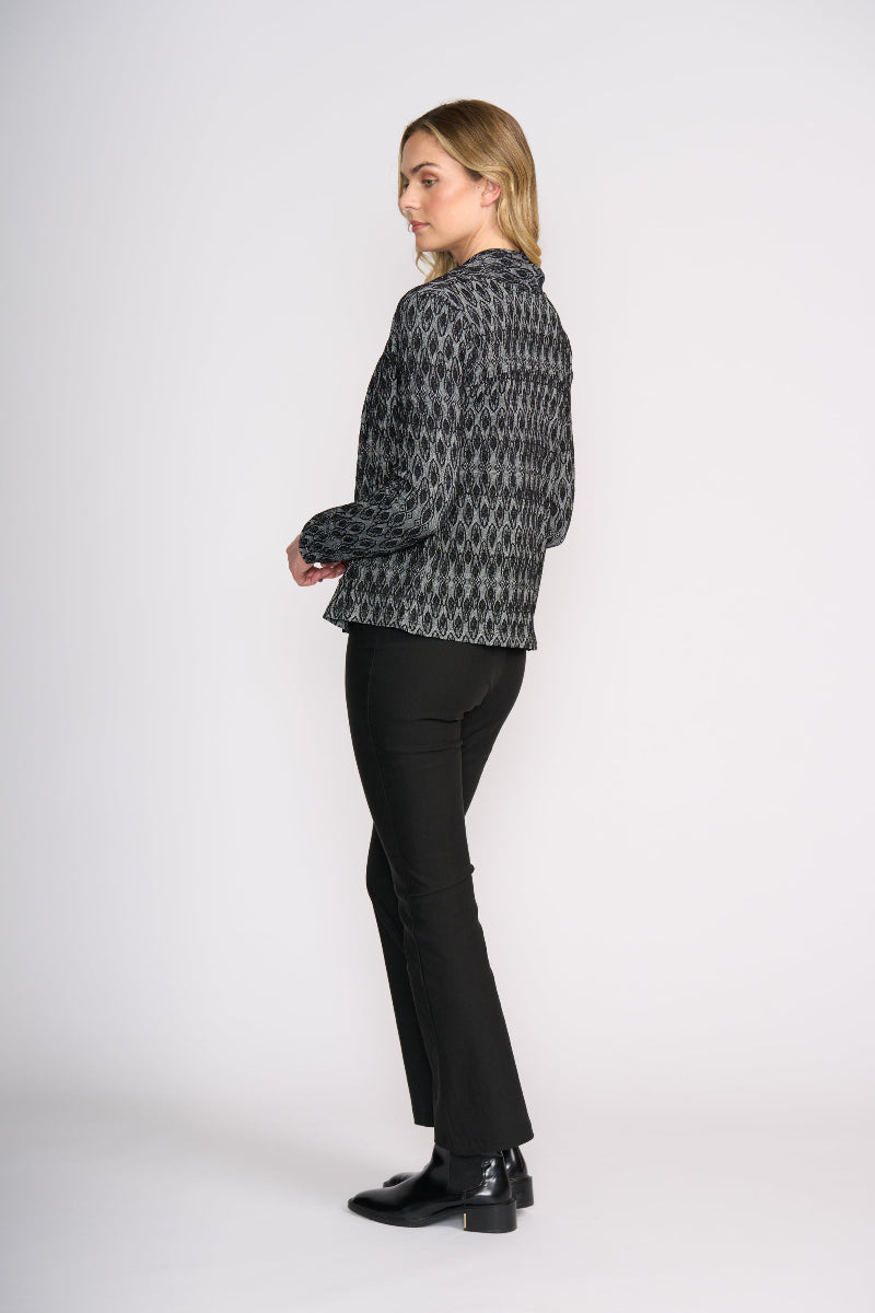 Woman wearing a patterned jacket and black pants on a white background