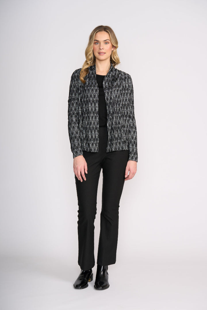 Woman wearing a patterned jacket and black pants on a white background