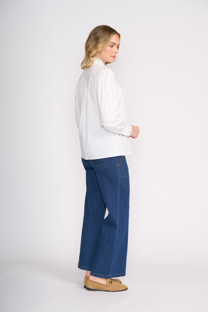 Woman wearing a white blouse and blue jeans on a white background