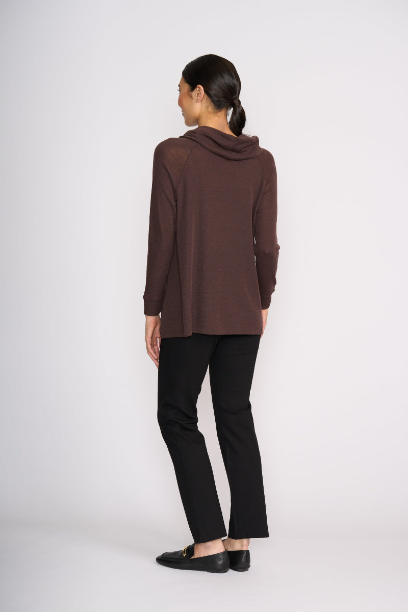 Woman wearing a brown cowl-neck sweater and black pants on a white background
