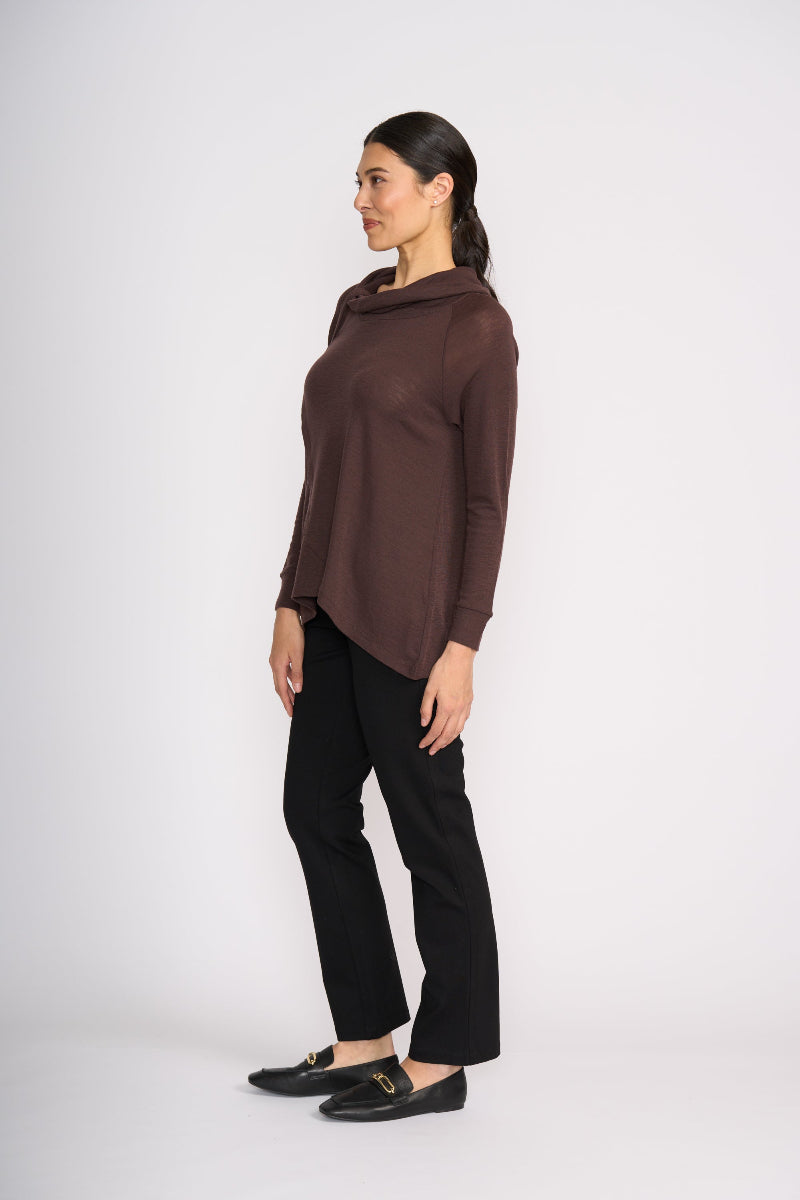 Woman wearing a brown cowl-neck sweater and black pants on a white background
