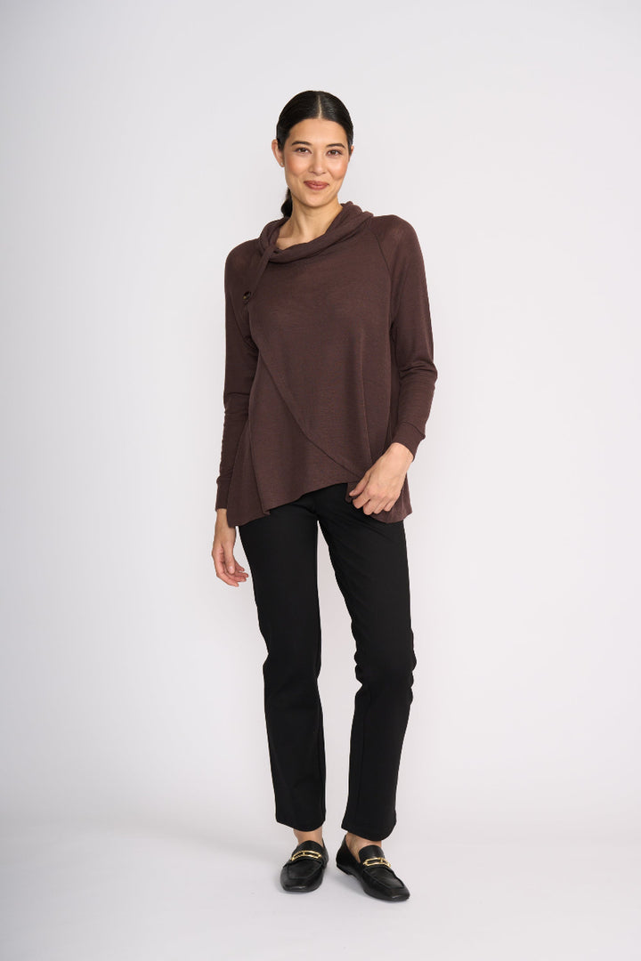 Woman wearing a brown cowl-neck sweater and black pants on a white background