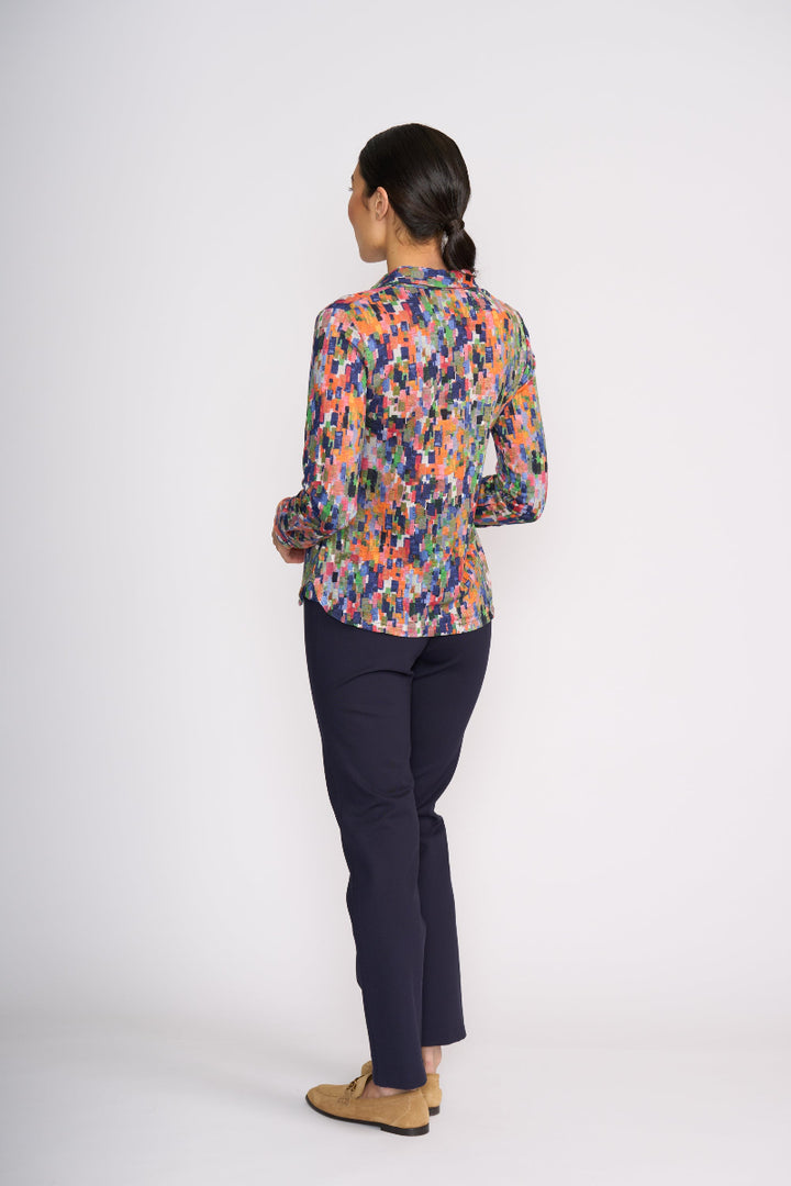 Person wearing a colorful floral blouse and dark pants on a white background