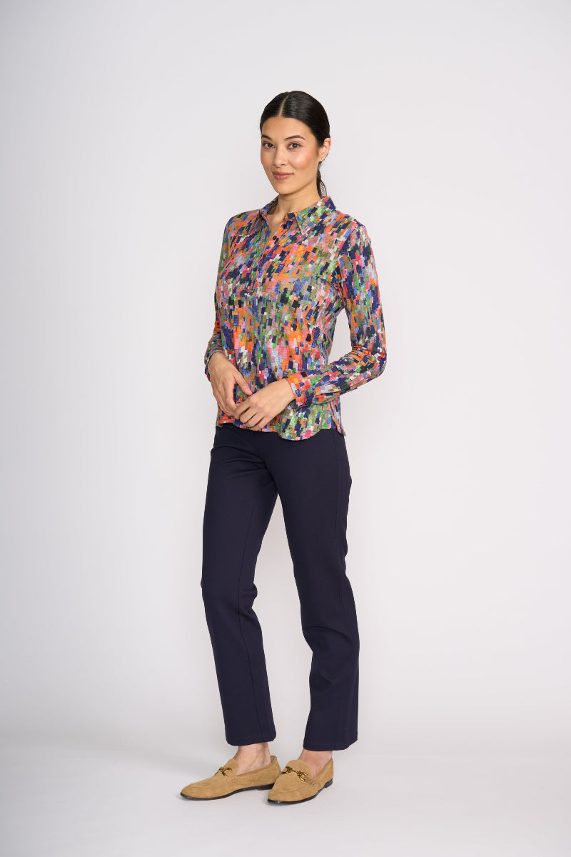 Woman wearing a colorful patterned shirt and dark pants on a white background