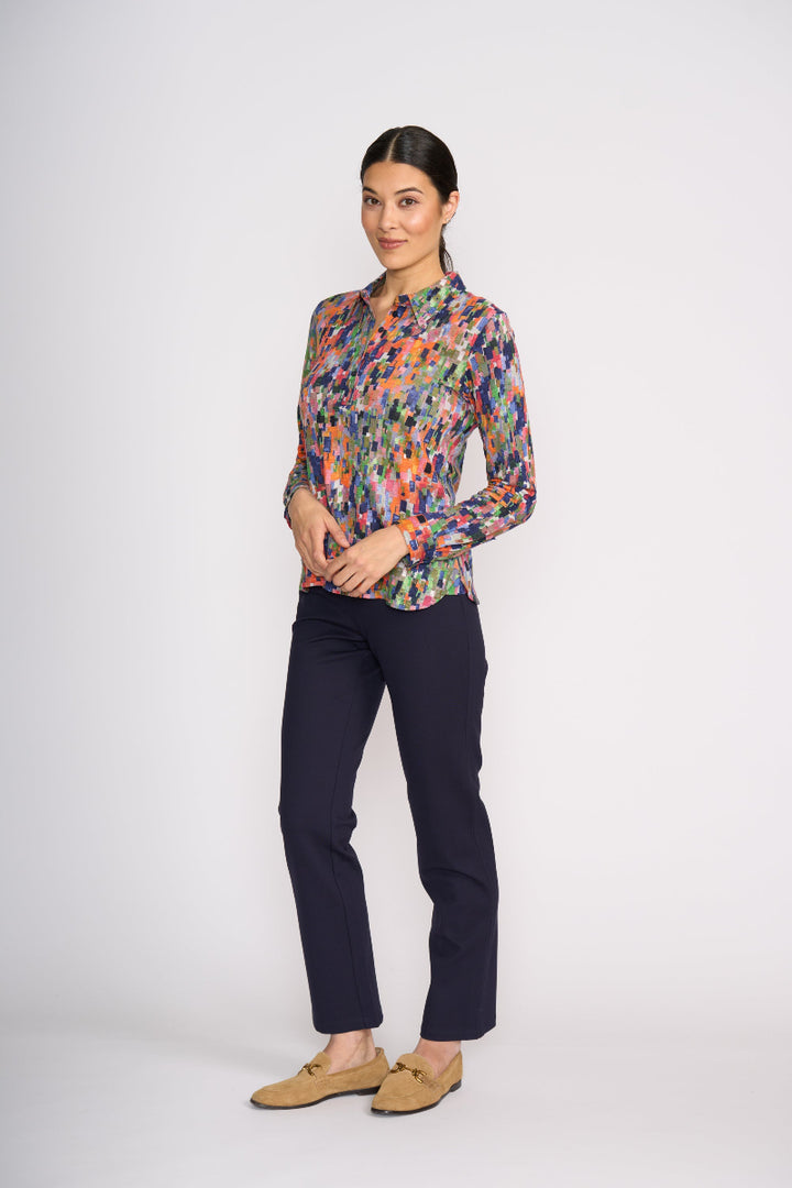 Woman wearing a colorful patterned shirt and dark pants on a white background