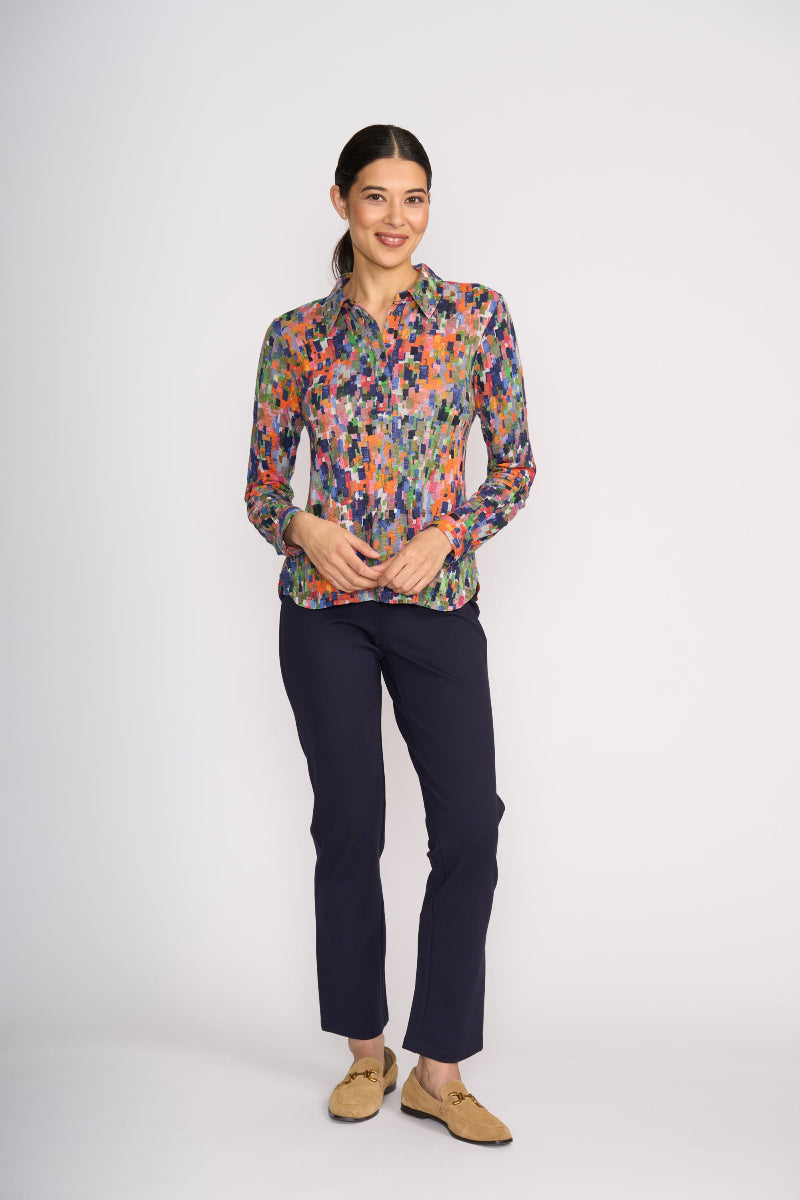 Woman wearing a colorful patterned shirt and dark pants on a white background