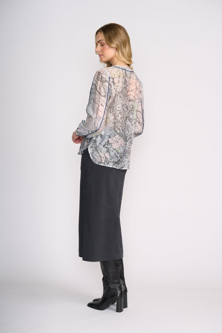 Woman wearing a floral blouse and black skirt with black boots on a white background