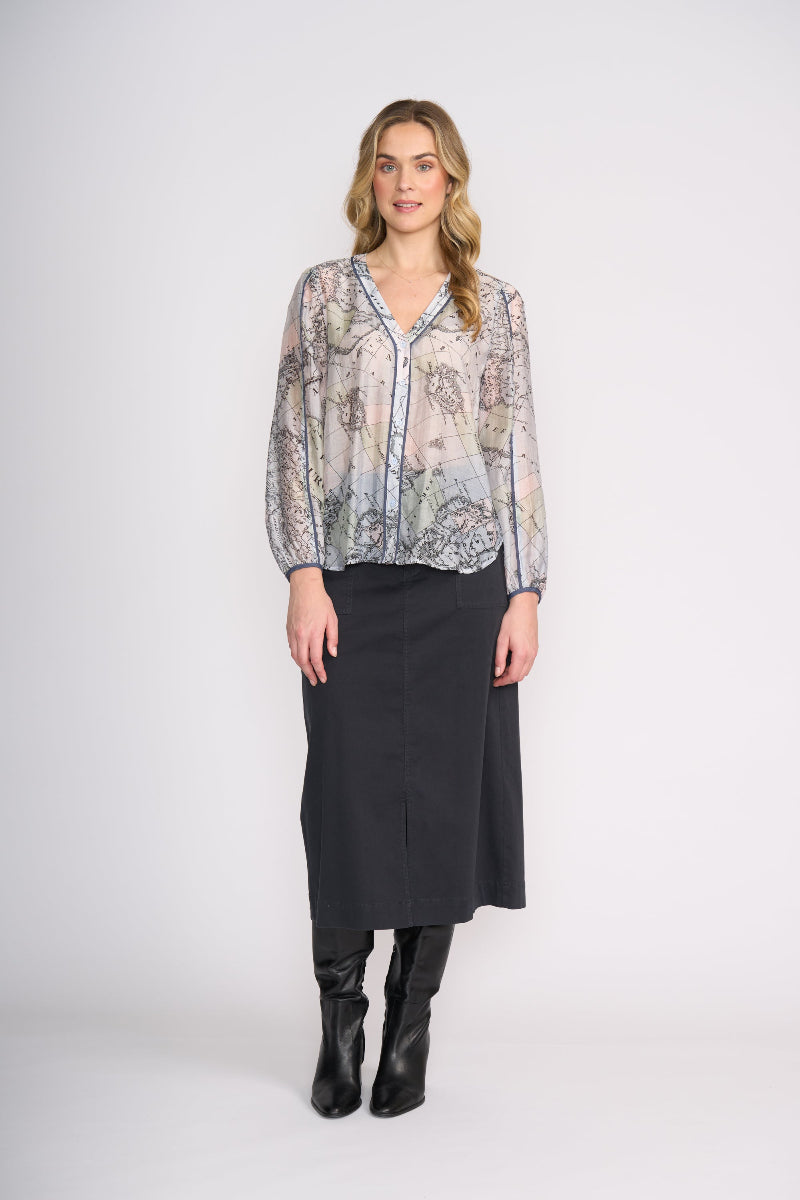 Woman wearing a patterned blouse and black skirt on a white background