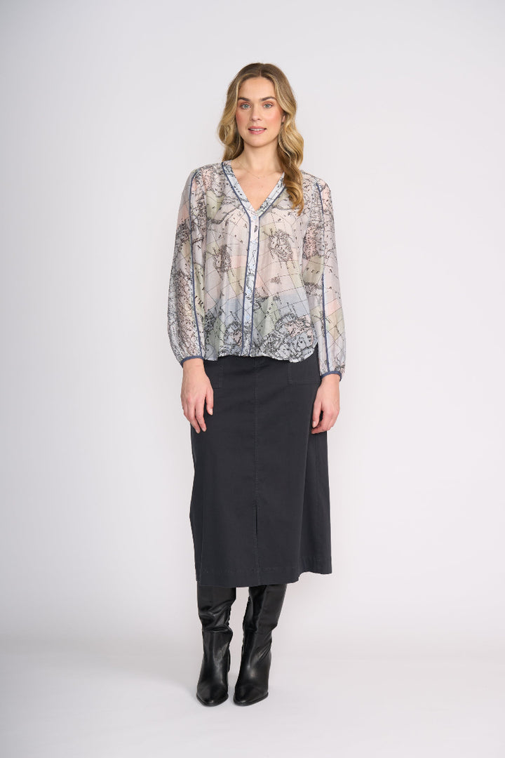 Woman wearing a patterned blouse and black skirt on a white background