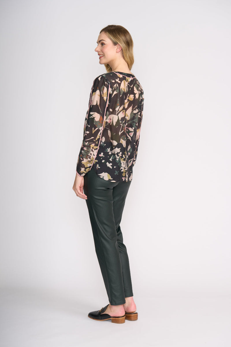 Woman wearing a floral blouse and green pants on a white background