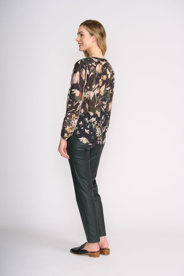 Woman wearing a floral blouse and green pants on a white background