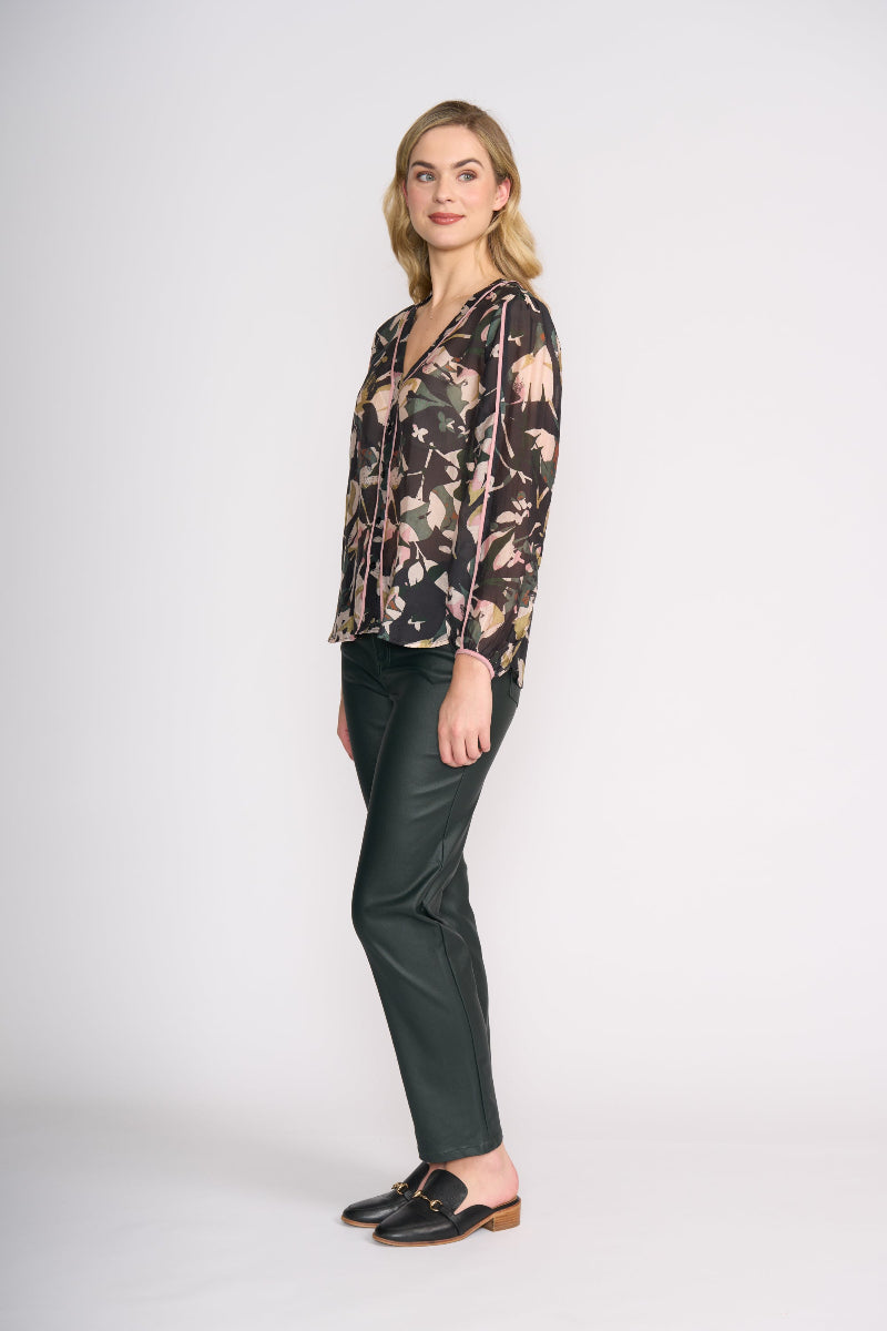 Woman wearing a floral blouse and dark pants on a white background