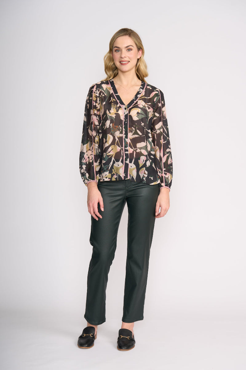 Woman wearing a floral blouse and black pants on a white background