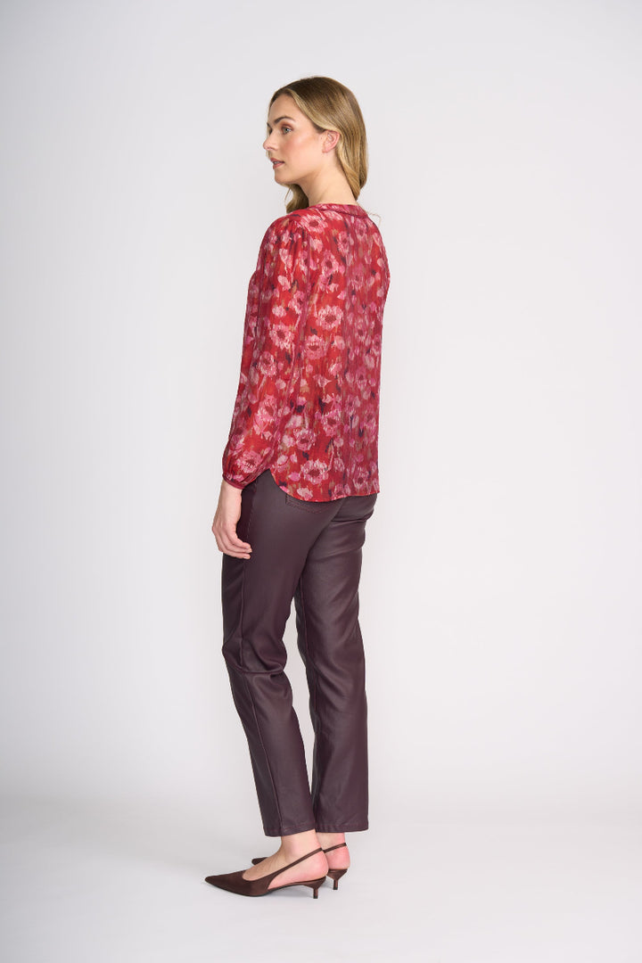 Woman wearing a red floral blouse and dark pants on a white background